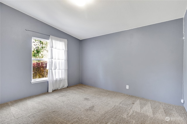 spare room with light carpet and vaulted ceiling