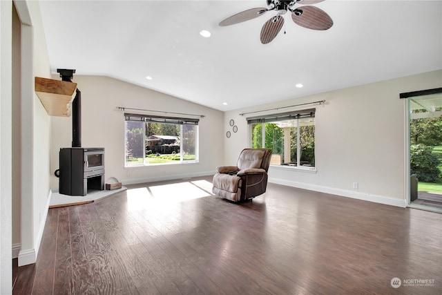 unfurnished room with a wood stove, dark wood-type flooring, a healthy amount of sunlight, and lofted ceiling