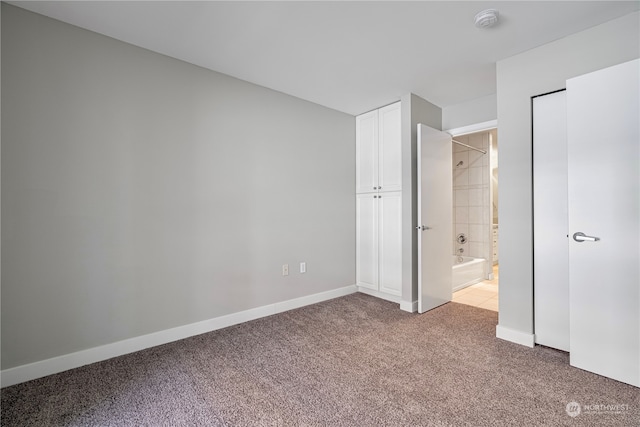 unfurnished bedroom with light carpet and connected bathroom