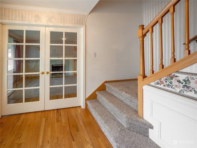 stairway featuring french doors, wood-type flooring, and ornamental molding