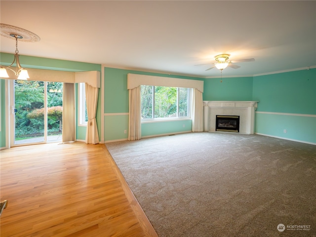 unfurnished living room featuring crown molding, hardwood / wood-style floors, and ceiling fan with notable chandelier