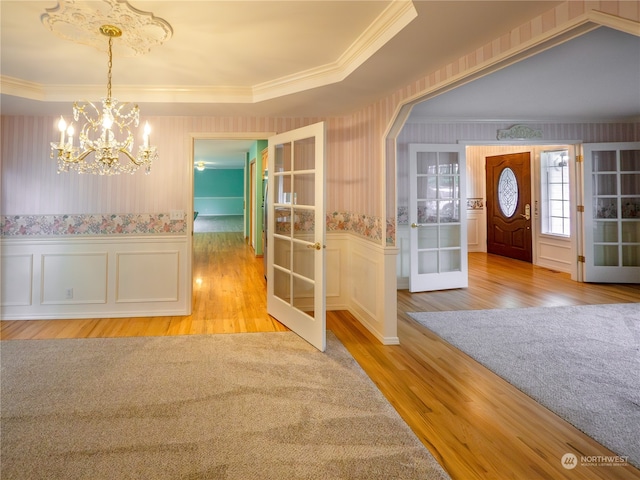 entrance foyer featuring french doors, light wood-type flooring, and a raised ceiling