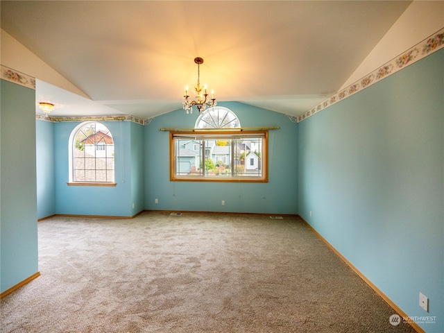 carpeted empty room with a chandelier and vaulted ceiling