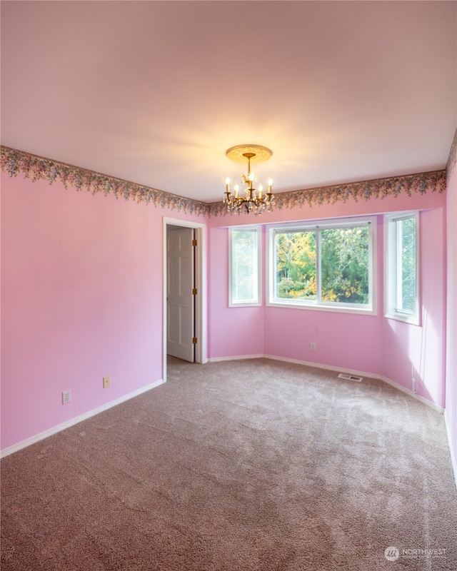 spare room with carpet and a chandelier