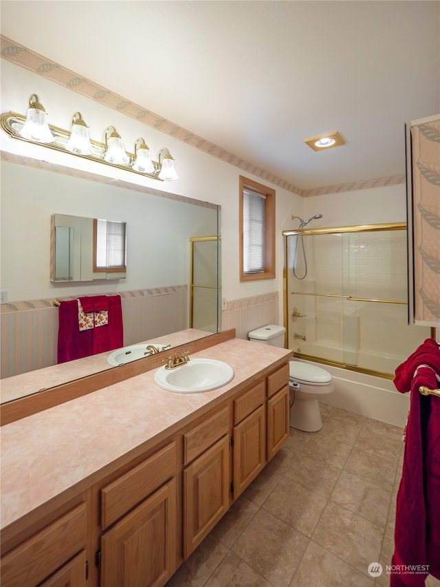 full bathroom featuring toilet, combined bath / shower with glass door, a healthy amount of sunlight, and vanity