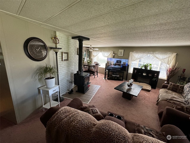 carpeted living room featuring a wood stove, a textured ceiling, and ceiling fan