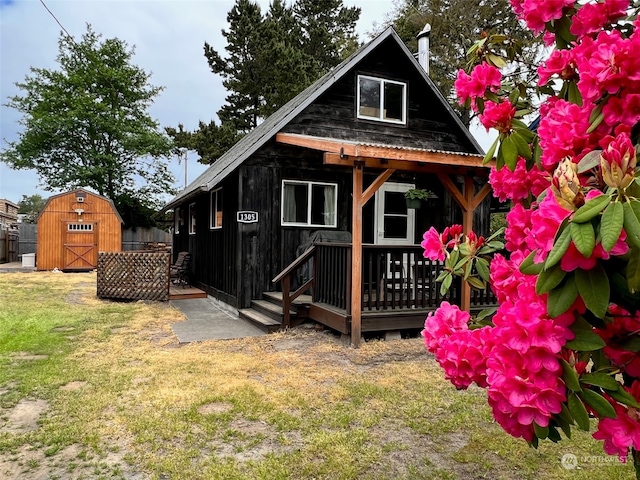 back of house with a lawn, a deck, and a shed