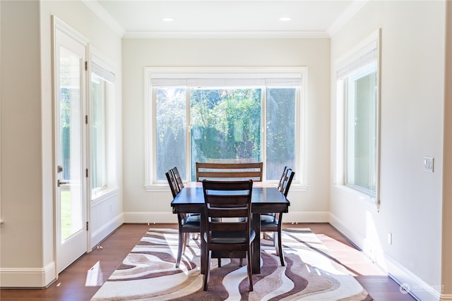 dining space featuring wood-type flooring, ornamental molding, and plenty of natural light