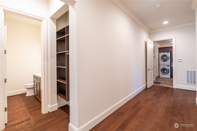 corridor with dark hardwood / wood-style flooring, crown molding, and stacked washer and clothes dryer