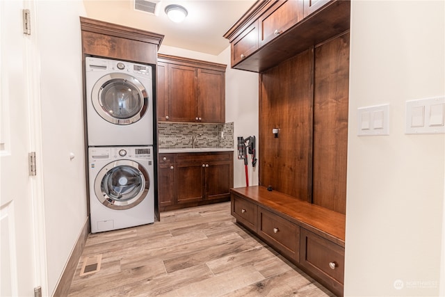 laundry area with cabinets, light hardwood / wood-style floors, and stacked washing maching and dryer