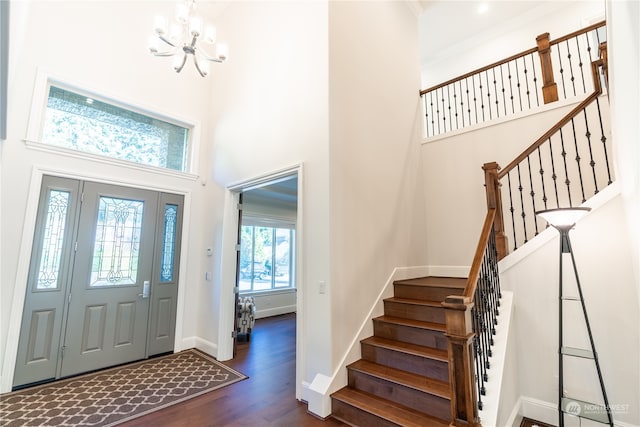 foyer entrance with an inviting chandelier, a towering ceiling, and dark hardwood / wood-style floors