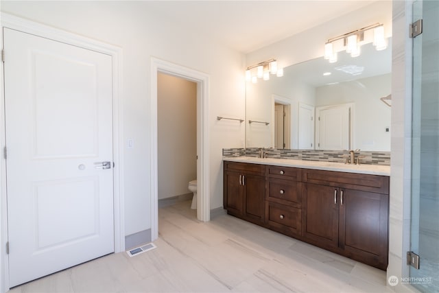 bathroom with vanity, toilet, and tasteful backsplash