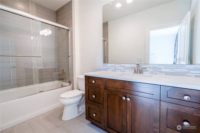 full bathroom with tile patterned flooring, decorative backsplash, bath / shower combo with glass door, vanity, and toilet