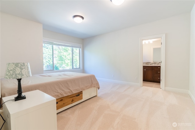 bedroom with ensuite bath and light colored carpet