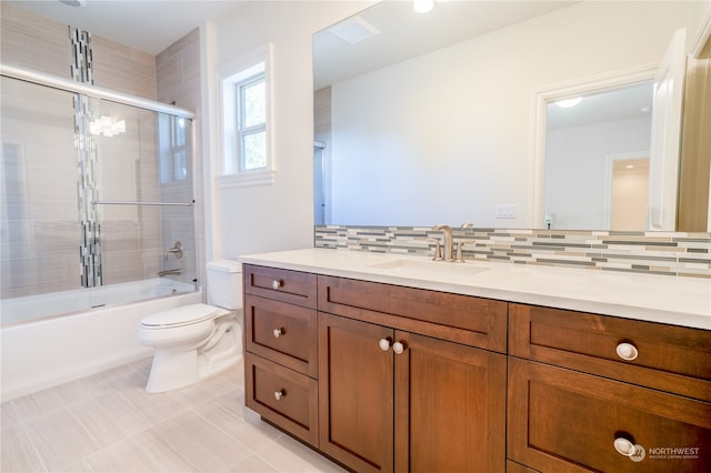 full bathroom featuring backsplash, enclosed tub / shower combo, vanity, and toilet