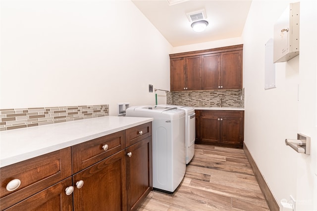 washroom with light wood-type flooring, sink, independent washer and dryer, and cabinets