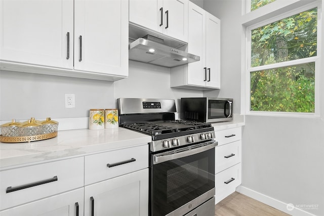 kitchen featuring stainless steel appliances, light stone countertops, white cabinetry, and light wood-type flooring