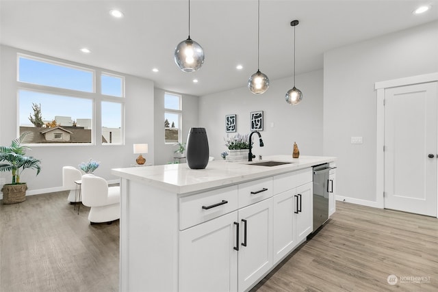 kitchen featuring light stone counters, white cabinetry, decorative light fixtures, sink, and dishwasher