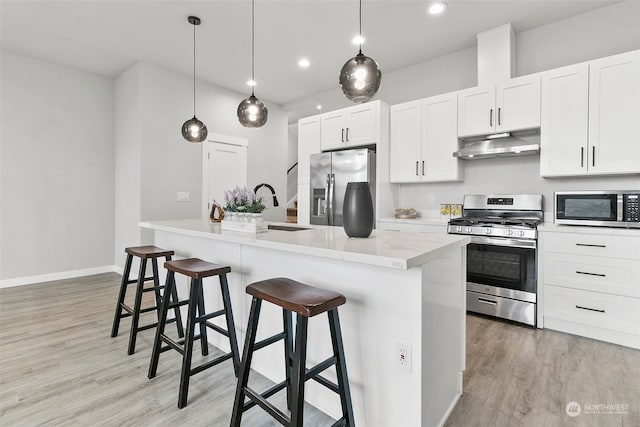 kitchen with stainless steel appliances, sink, a breakfast bar, white cabinetry, and decorative light fixtures