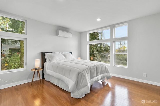 bedroom featuring a wall mounted AC and hardwood / wood-style flooring