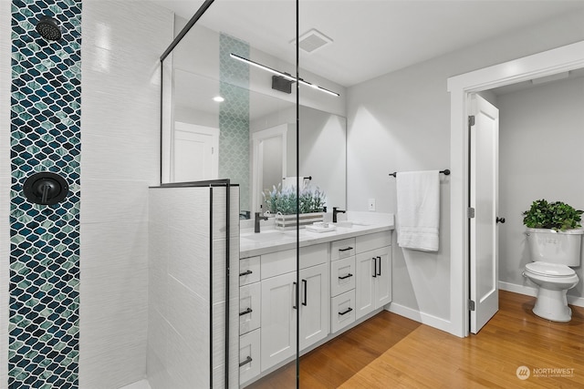 bathroom featuring hardwood / wood-style flooring, vanity, toilet, and a tile shower