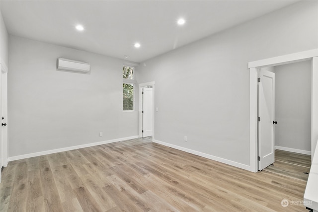 spare room featuring a wall mounted AC and light hardwood / wood-style flooring