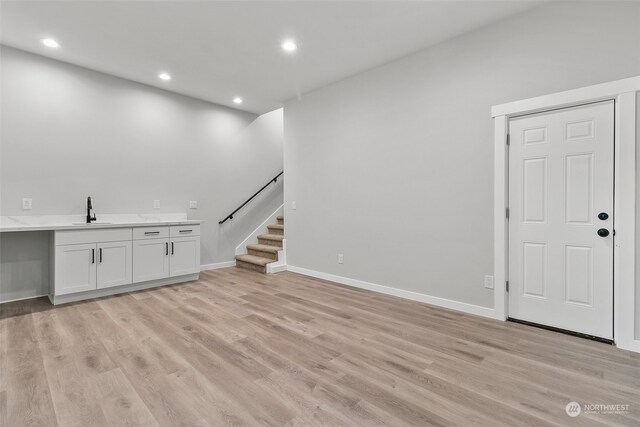 unfurnished living room featuring sink and light hardwood / wood-style flooring