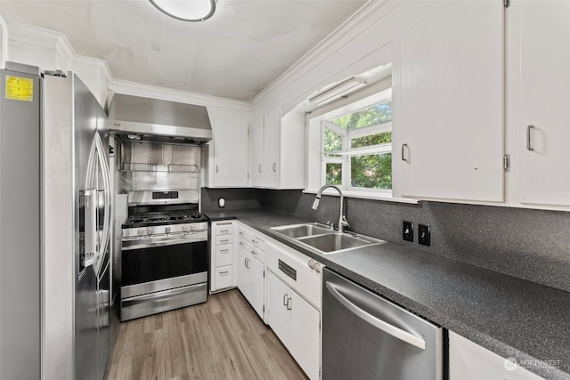 kitchen with appliances with stainless steel finishes, light hardwood / wood-style floors, white cabinets, sink, and wall chimney range hood