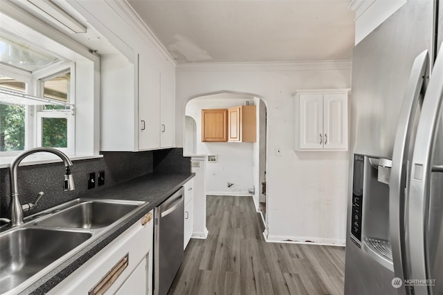 kitchen with white cabinets, stainless steel appliances, crown molding, hardwood / wood-style flooring, and sink