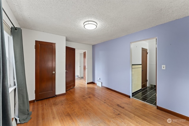 unfurnished bedroom featuring ensuite bath, a textured ceiling, and dark hardwood / wood-style flooring