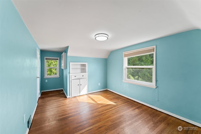 unfurnished bedroom with lofted ceiling, hardwood / wood-style floors, and multiple windows