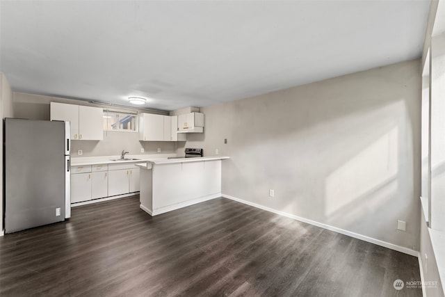 kitchen with dark wood-type flooring, sink, white cabinets, kitchen peninsula, and appliances with stainless steel finishes