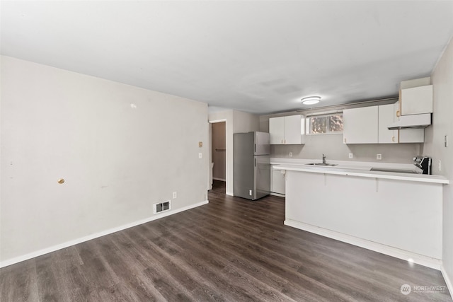 kitchen featuring white cabinets, stainless steel fridge, kitchen peninsula, electric range oven, and dark hardwood / wood-style flooring