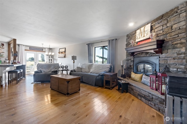 living room featuring french doors, light hardwood / wood-style floors, and a fireplace