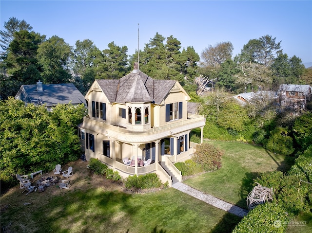 back of house featuring a balcony and a lawn