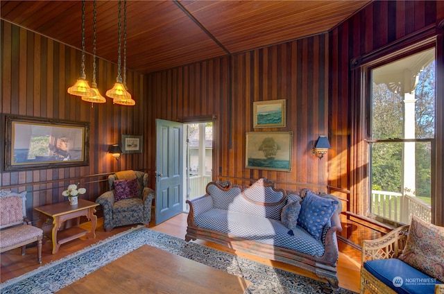 living room with wooden ceiling, wooden walls, and light wood-type flooring