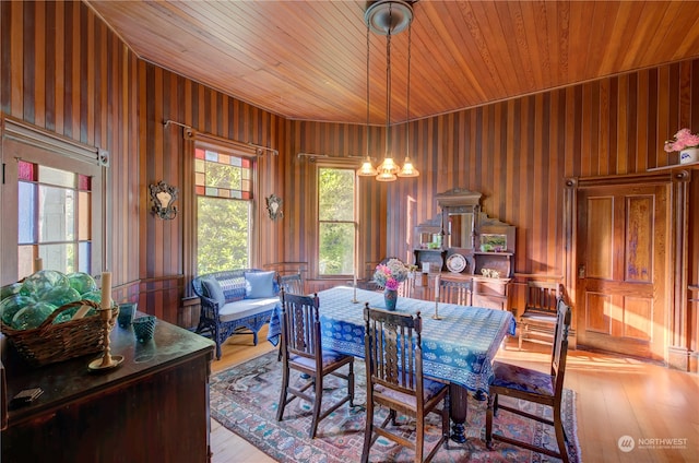 dining space featuring wooden ceiling, light hardwood / wood-style floors, wooden walls, and a chandelier