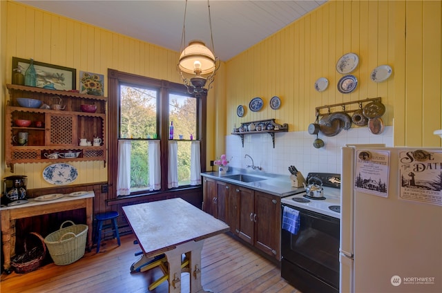 kitchen featuring light wood-type flooring, sink, white fridge, decorative backsplash, and black range with electric cooktop