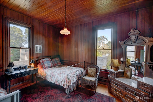 bedroom featuring light wood-type flooring, wood walls, multiple windows, and wooden ceiling