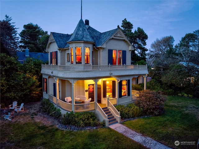 victorian house featuring a balcony, covered porch, and a yard