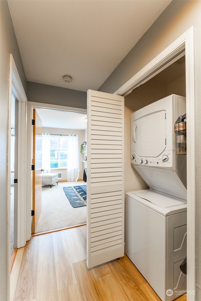 clothes washing area with stacked washer / dryer and light hardwood / wood-style floors