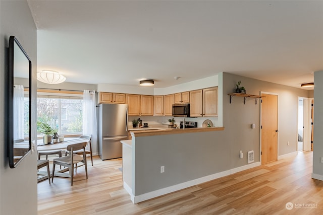 kitchen featuring kitchen peninsula, light wood-type flooring, stainless steel appliances, and light brown cabinetry