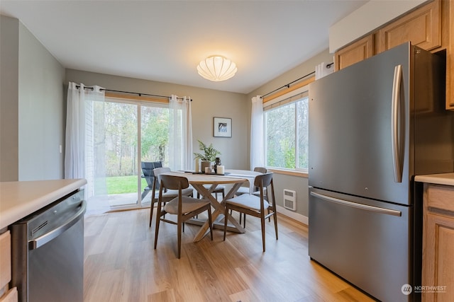 dining space featuring light wood-type flooring and a healthy amount of sunlight