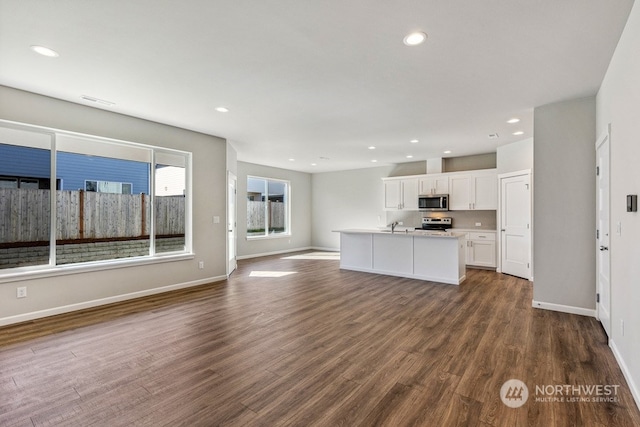 kitchen featuring white cabinets, sink, a center island with sink, dark wood-type flooring, and stainless steel appliances