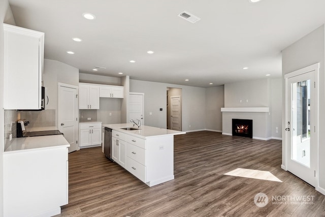 kitchen with white cabinets, sink, black range, a center island with sink, and dark hardwood / wood-style flooring