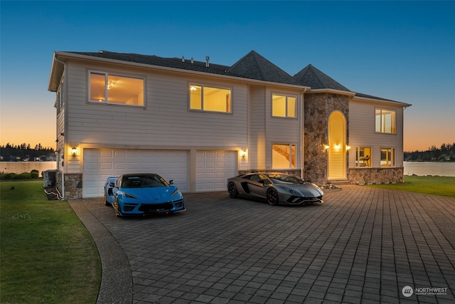 view of front facade featuring cooling unit, a garage, a lawn, and a water view