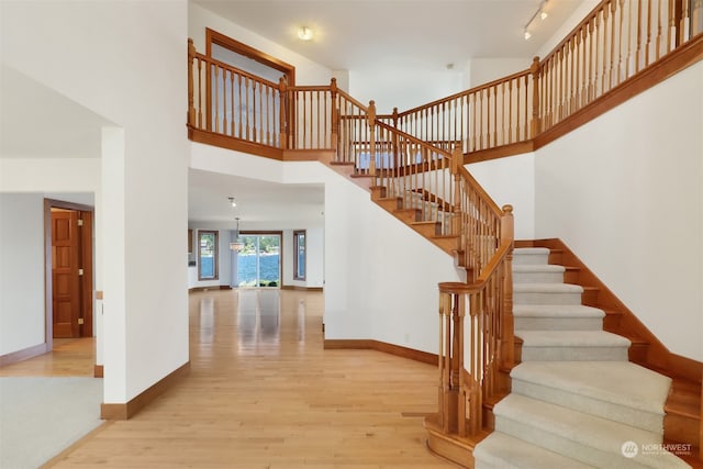 staircase with a high ceiling, an inviting chandelier, and wood-type flooring