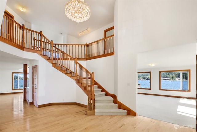 stairs with high vaulted ceiling, a chandelier, and wood-type flooring