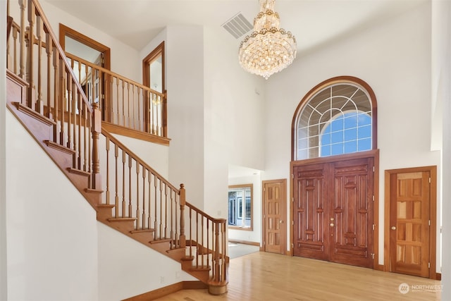 foyer featuring wood-type flooring, a high ceiling, and a notable chandelier