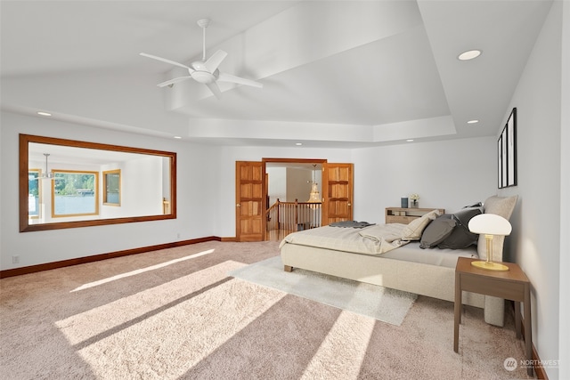 carpeted bedroom featuring a raised ceiling and ceiling fan